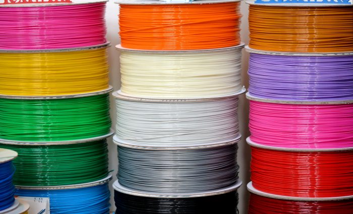 Reels of plastic for 3D printer close-up. Reels of filament wire for 3D printer different colors. Material produced from FDM printing technology. Many reels vertical view. Abstract modern background